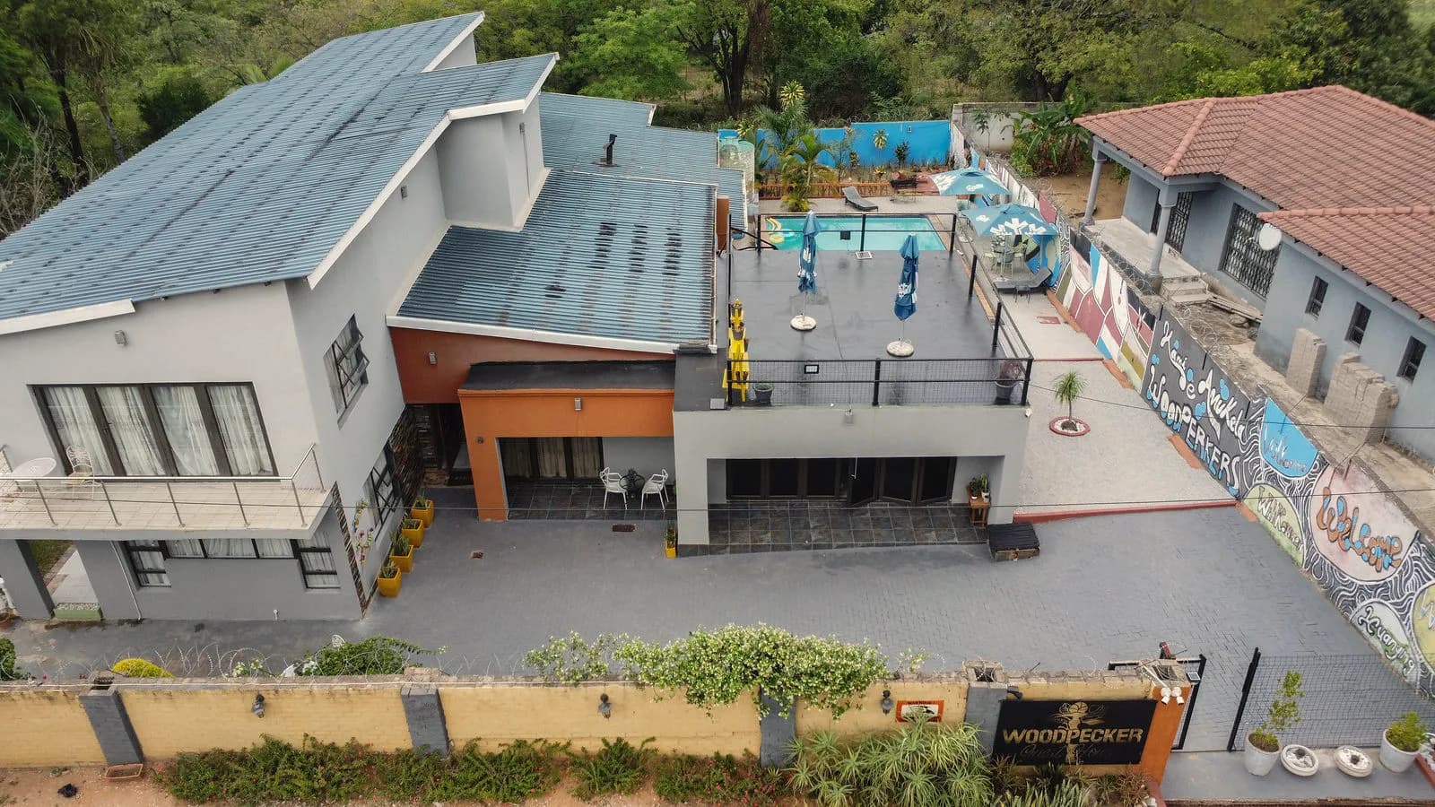 Woodpecker Guesthouse from the air: the house, the pool deck and the painted garden walls